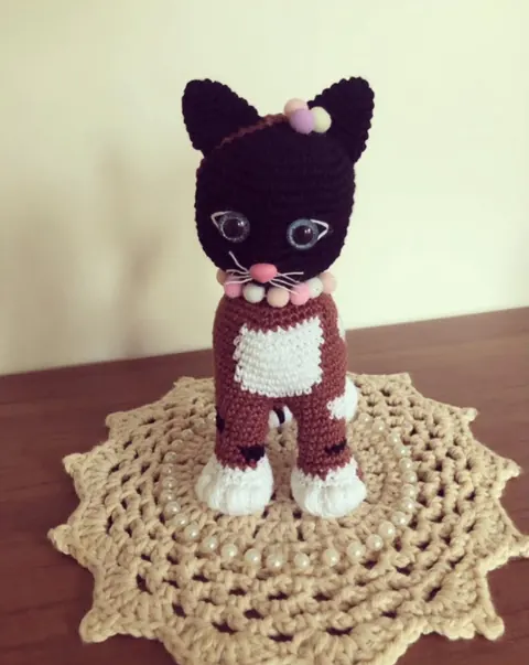 Antes do curso: gato de crochê preto e vinho sobre uma toalhinha